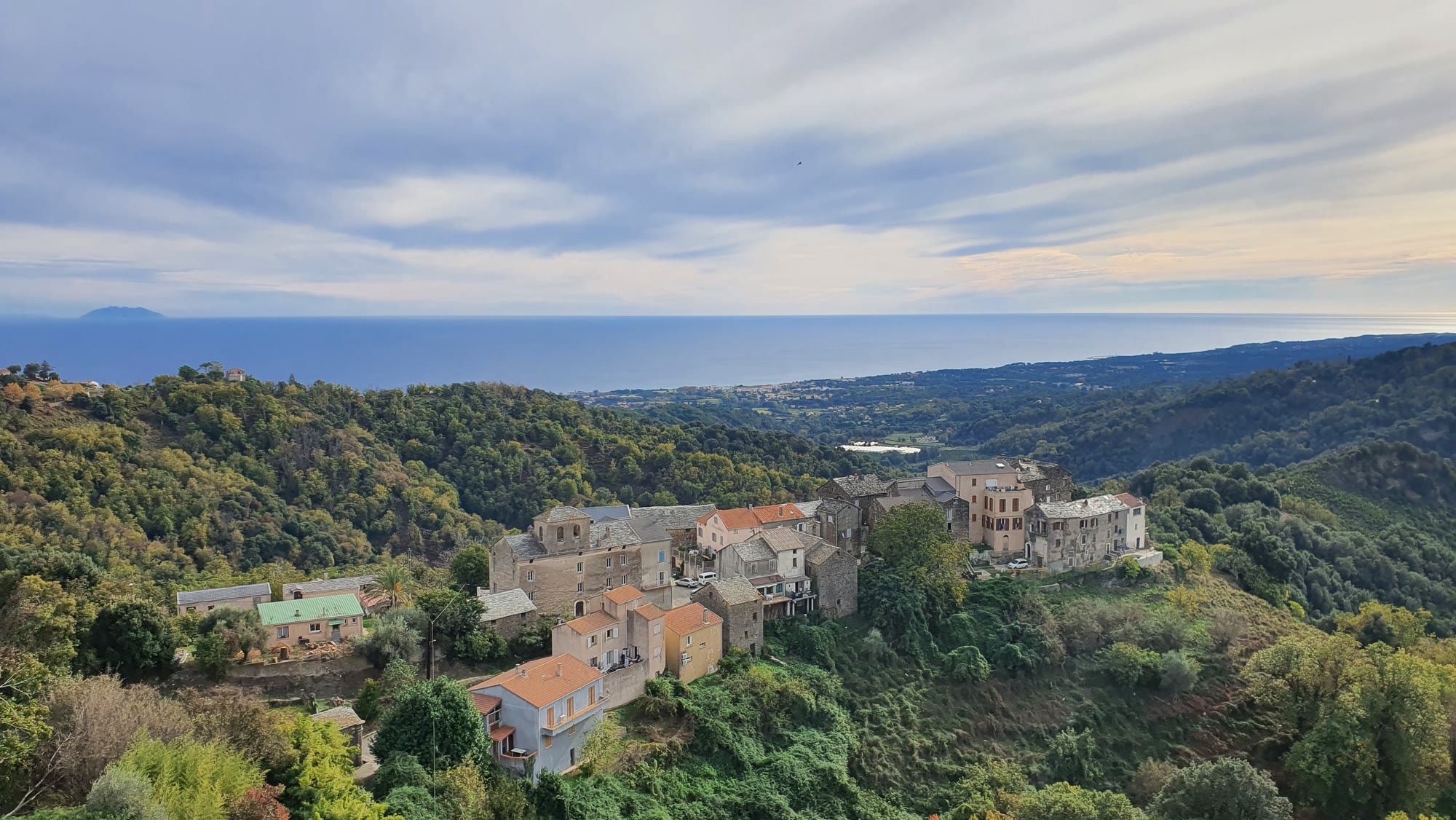 Village accroché à la colline, la plaine orientale et la mer au loin